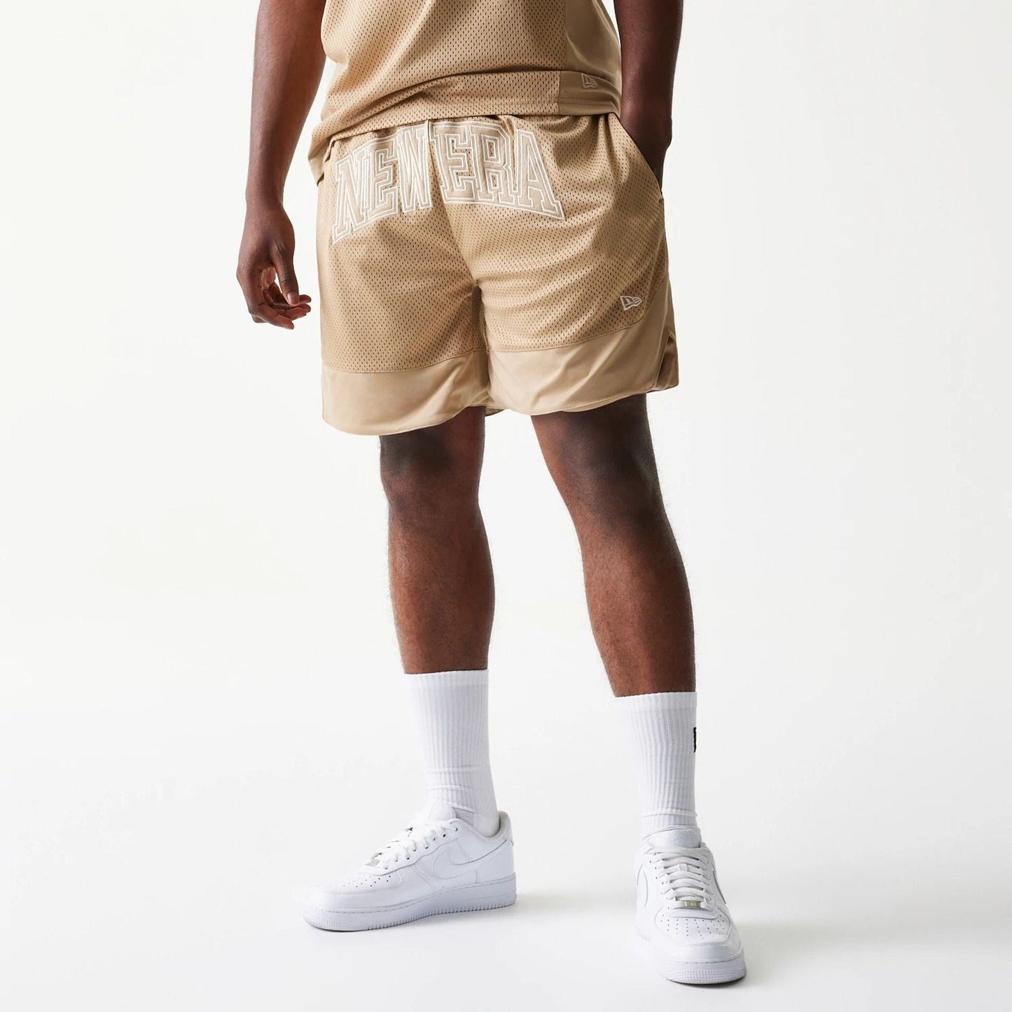 The model is wearing this New Era Mesh Graphic Oversized Shorts in light beige. 1