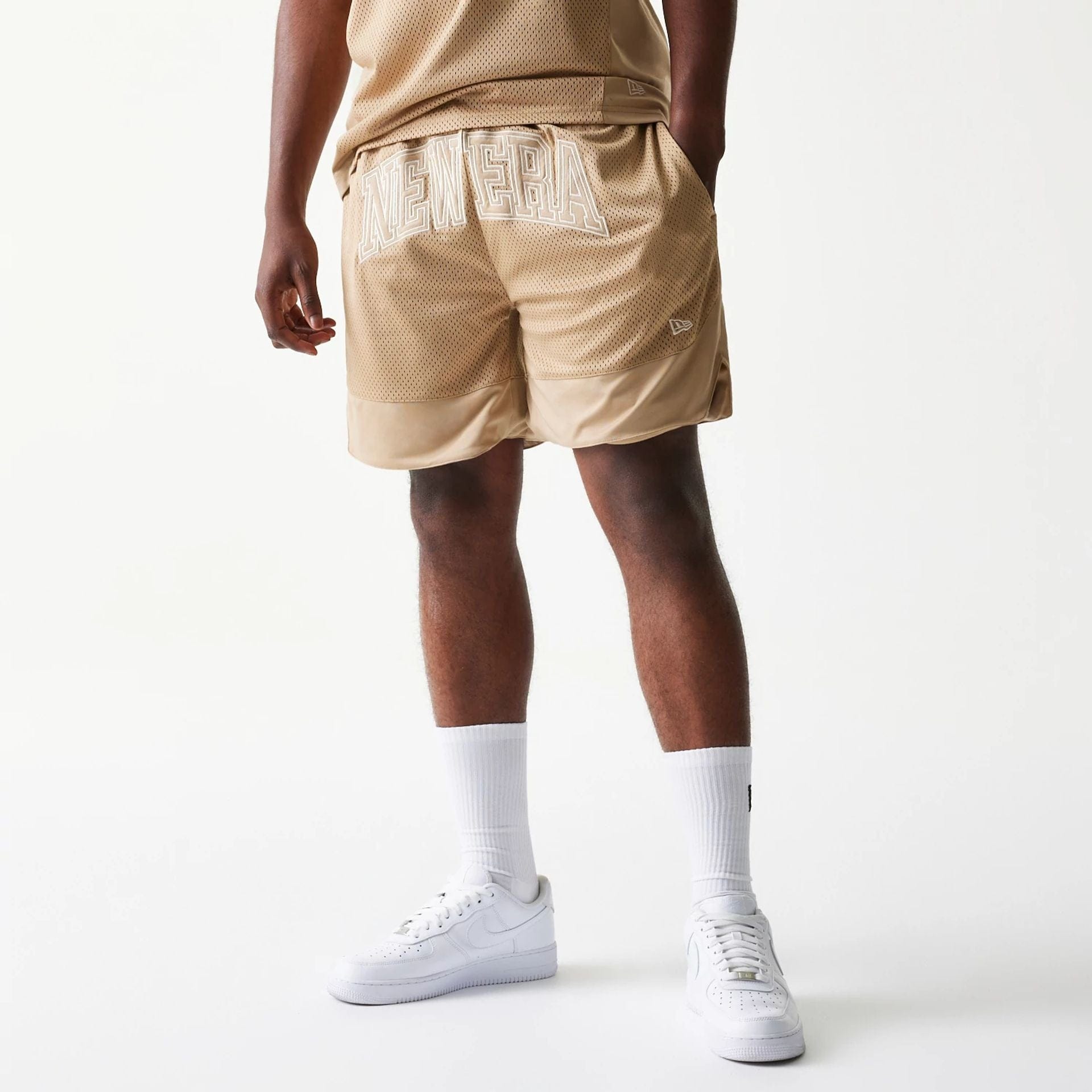 The model is wearing this New Era Mesh Graphic Oversized Shorts in light beige. 1