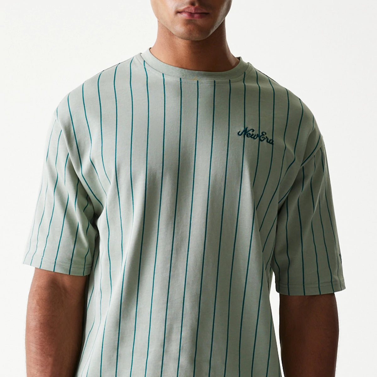 The model is wearing this New Era Pinstripe Oversized T-Shirt in pastel green. 3