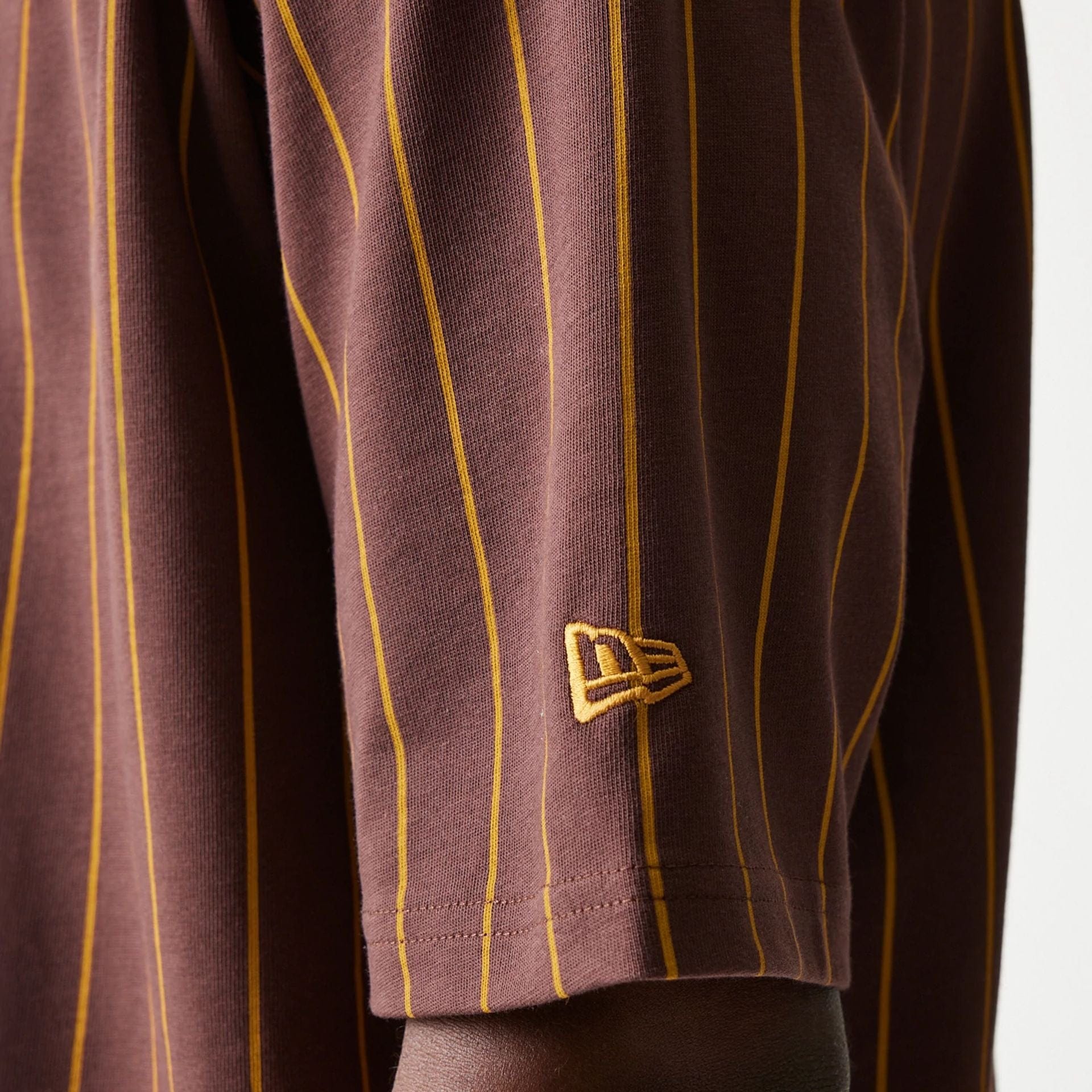 The model is wearing this New Era Pinstripe Oversized T-Shirt in brown. 5