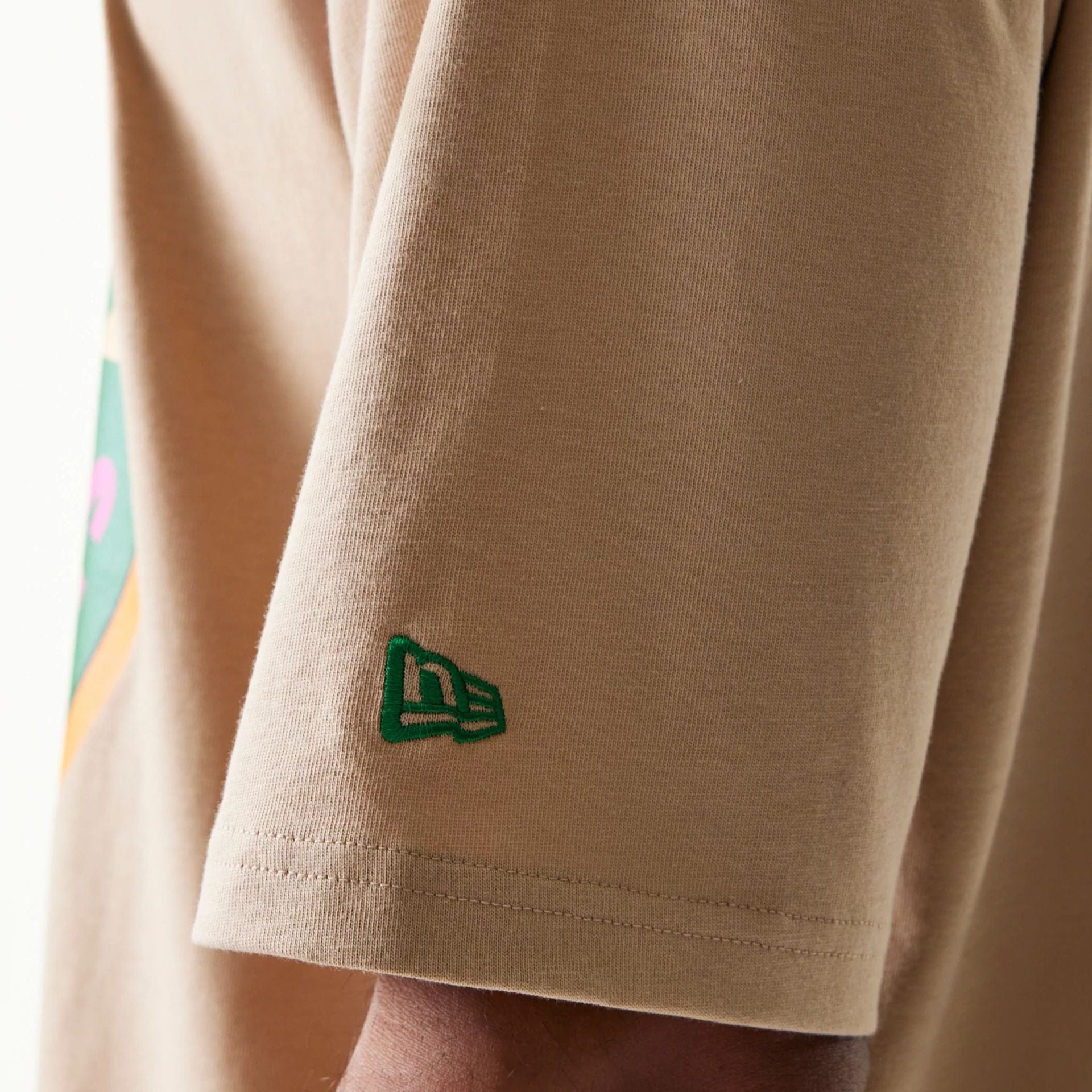 The model is wearing this New Era Orange Fruit Graphic Oversized T-Shirt in light beige. 5