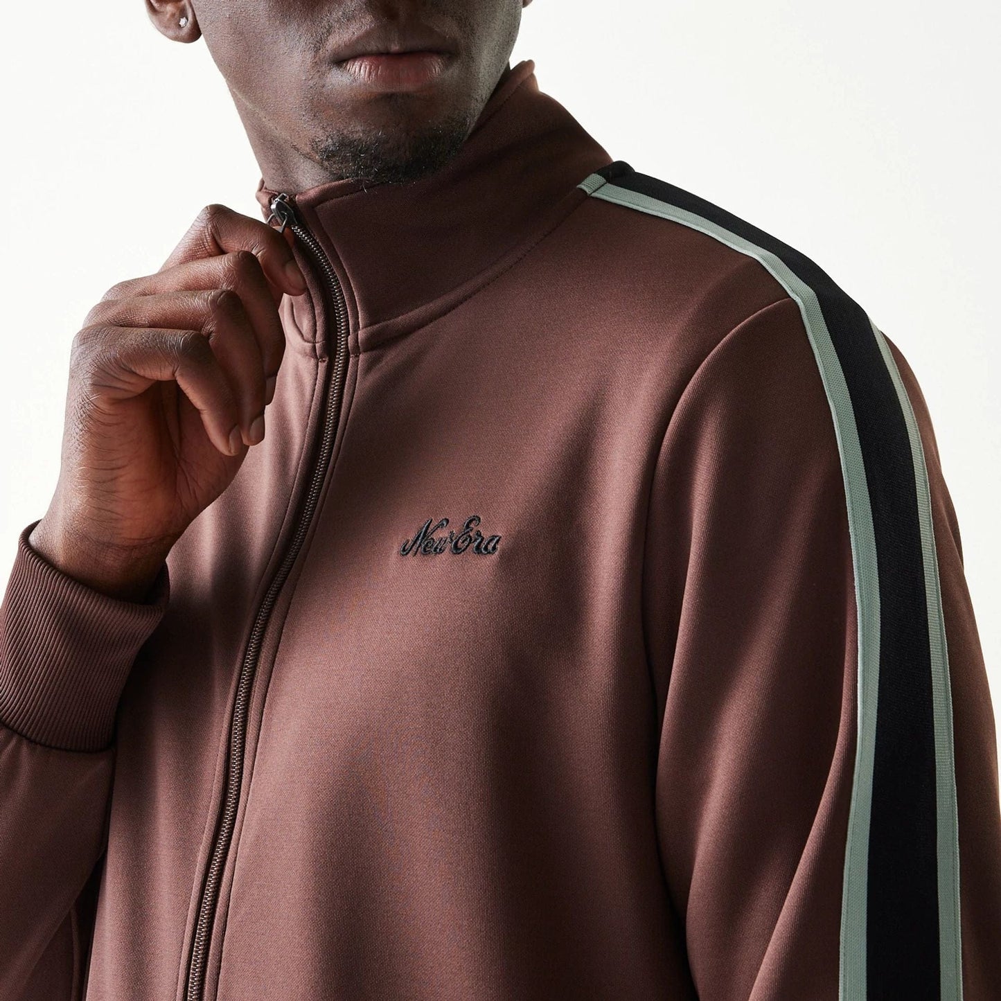 The model is wearing this New Era Script Track Jacket in brown. 6
