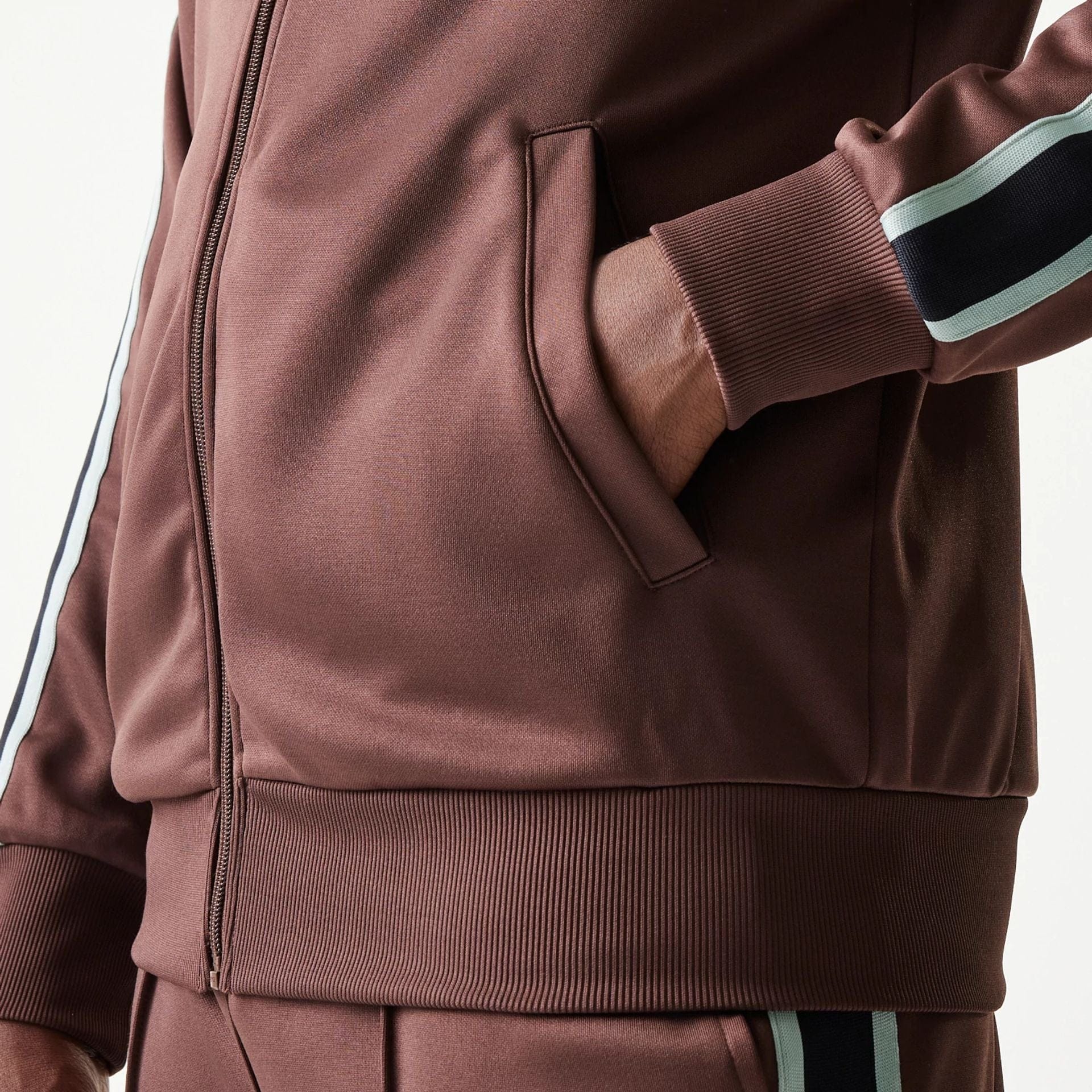 The model is wearing this New Era Script Track Jacket in brown. 7