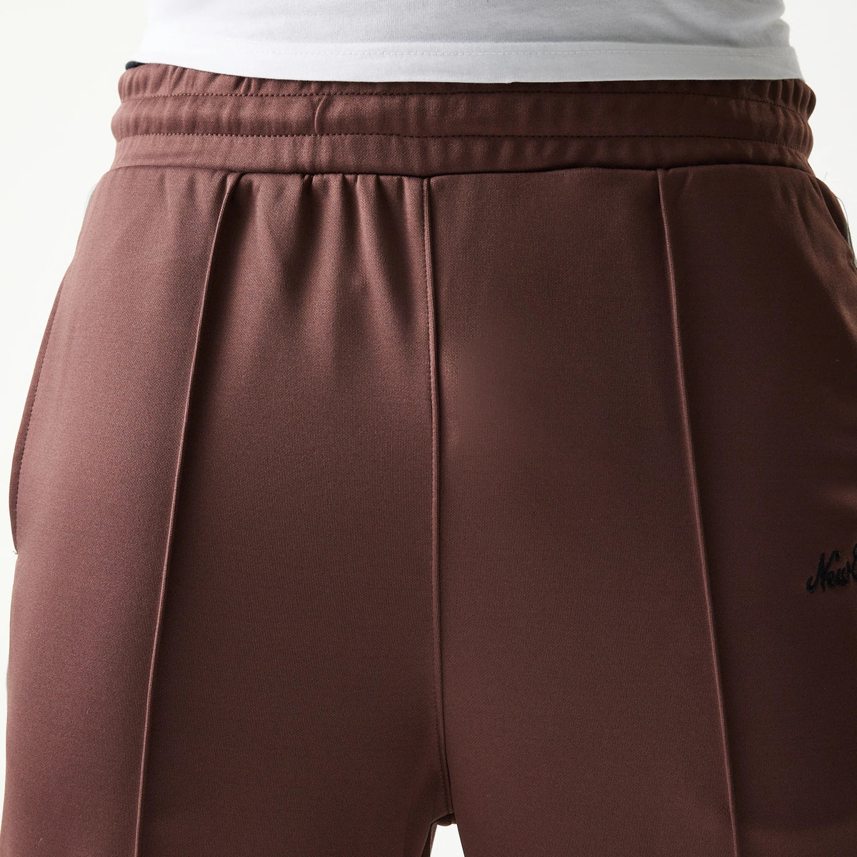 New Era Script Brown Straight Leg Joggers, front view showing the brown colour with a pleated design and elastic waistband, featuring a black New Era script logo on the right side.