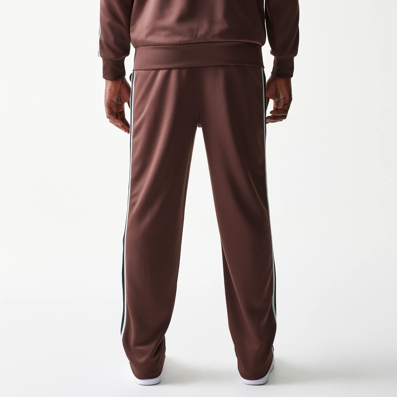 New Era Script Brown Straight Leg Joggers, rear view on a model showing the relaxed fit with white side stripes, elasticated waistband, and straight leg design highlighting the brown fabric.