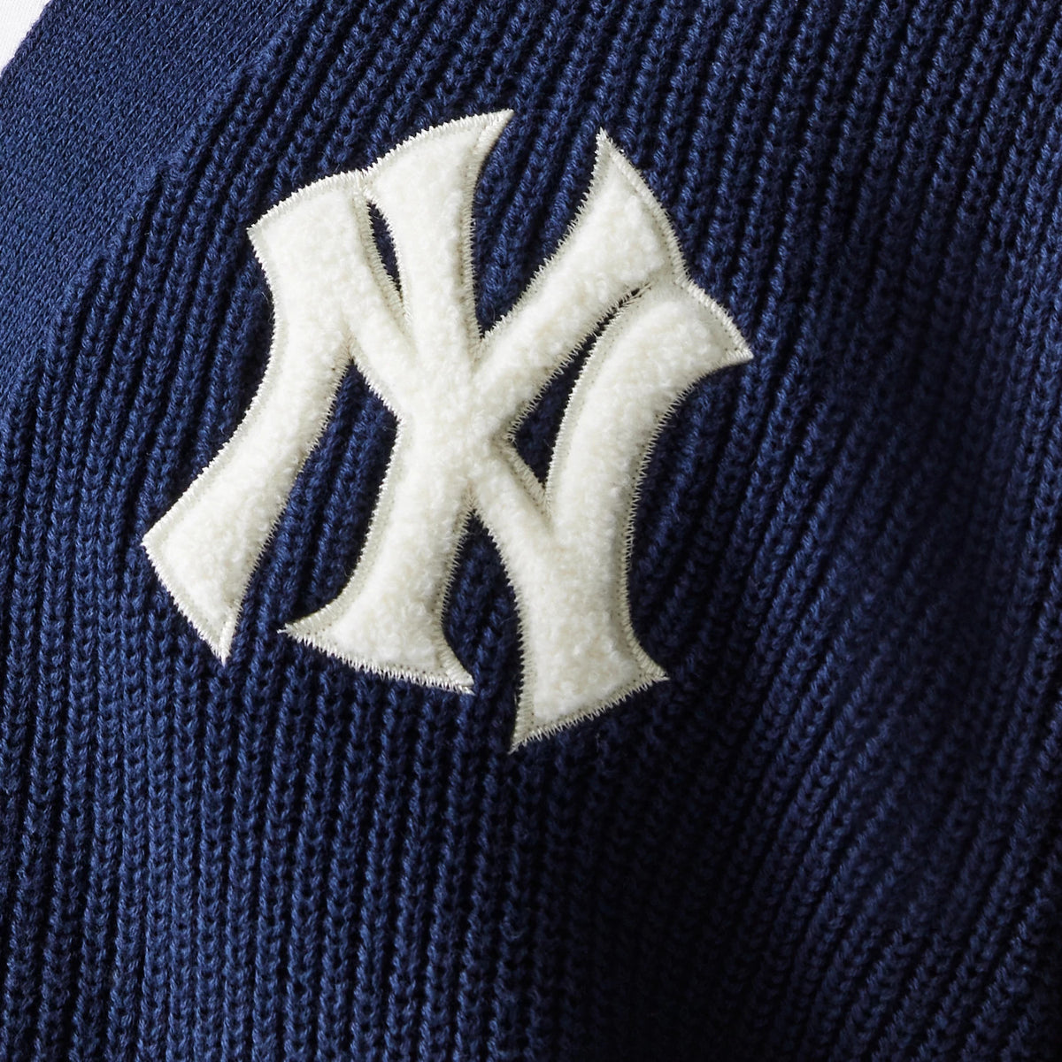 New Era New York Yankees MLB Collegiate Navy Cardigan, close-up showing the textured white New York Yankees logo in chenille material on the ribbed navy fabric, highlighting the intricate knit pattern.