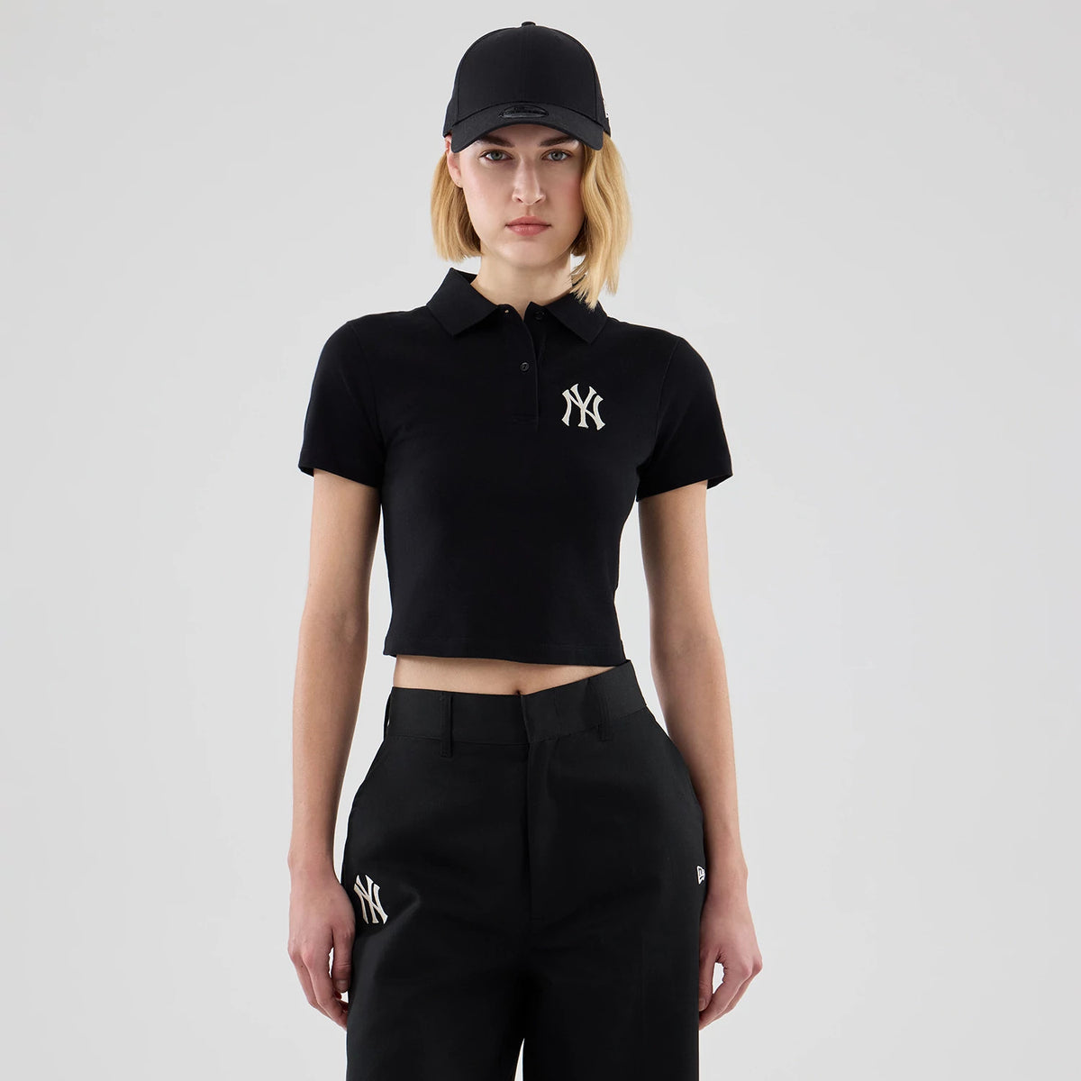 The model is wearing this Womens MLB New York Yankees Cropped Slim Polo T-shirt in black. 1