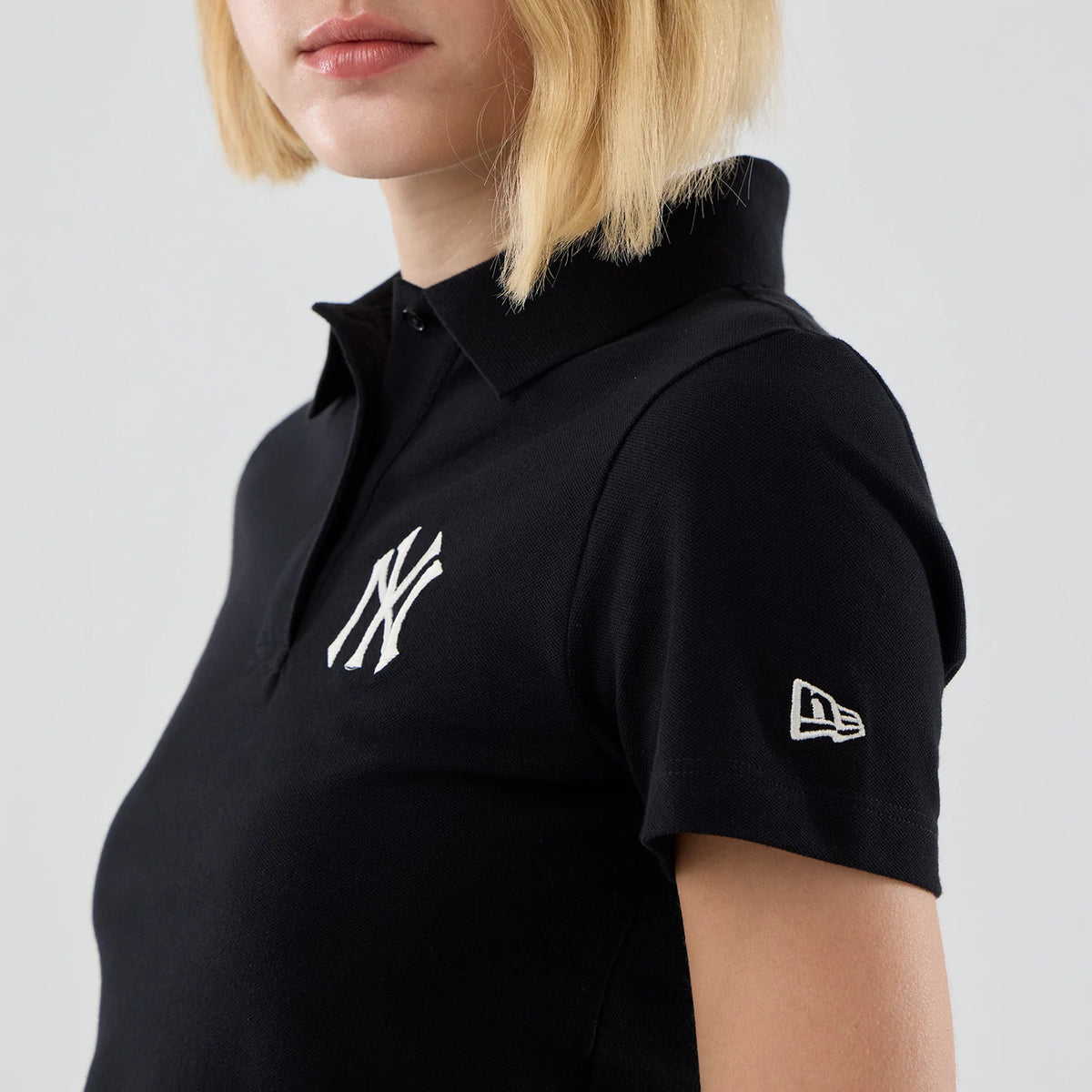 The model is wearing this Womens MLB New York Yankees Cropped Slim Polo T-shirt in black. 5
