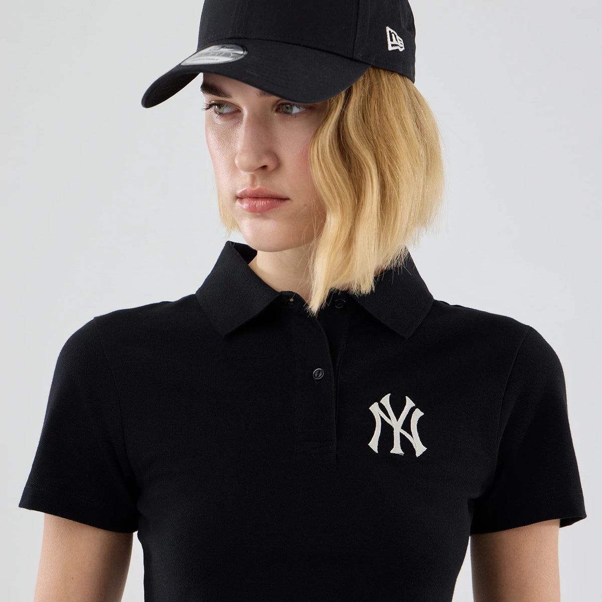 The model is wearing this Womens MLB New York Yankees Cropped Slim Polo T-shirt in black. 6
