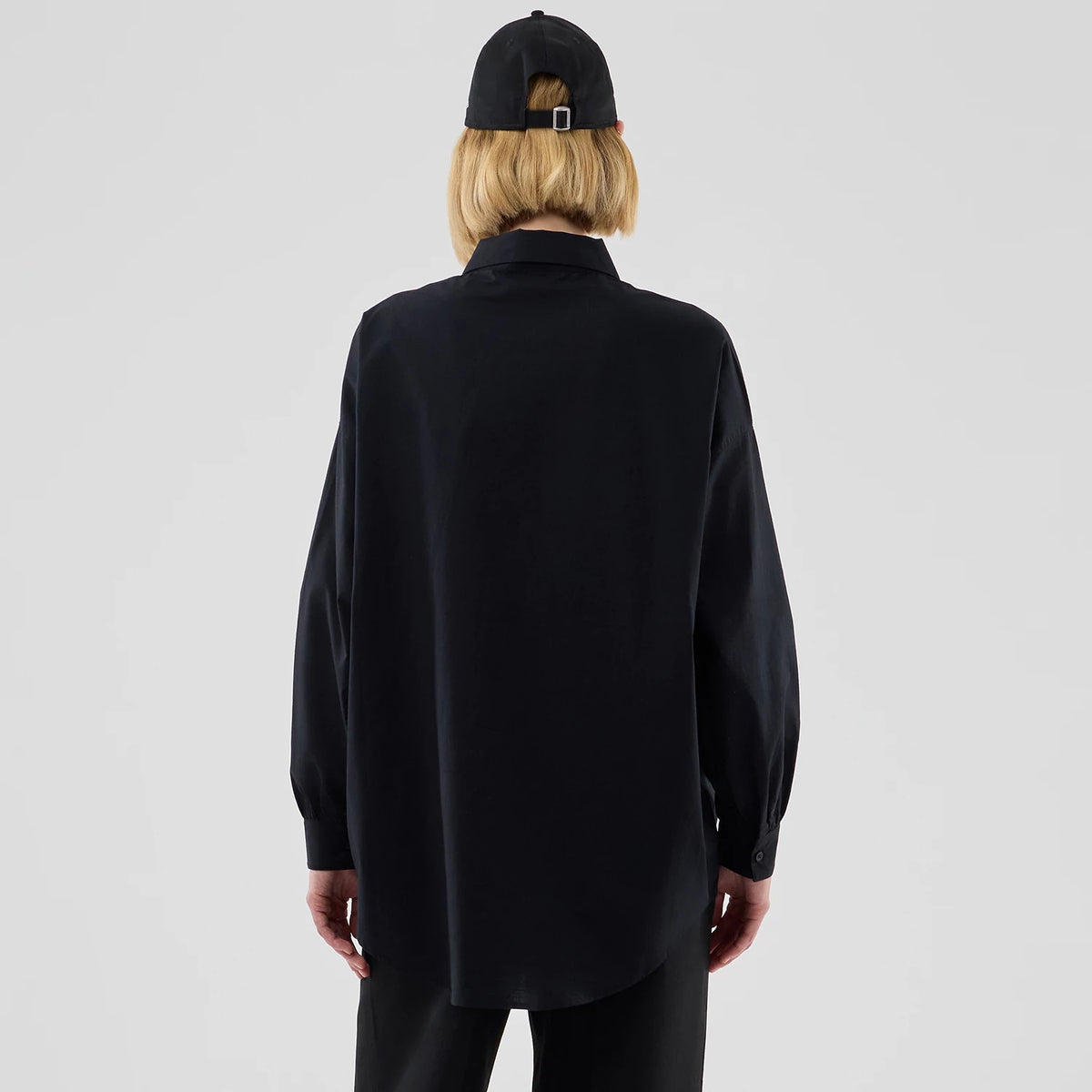 New Era New York Yankees Womens MLB Shirt Black Long Sleeve Shirt, back view on a model wearing a black cap, featuring a loose fit with a curved hem, long sleeves with buttoned cuffs, and a classic pointed collar.