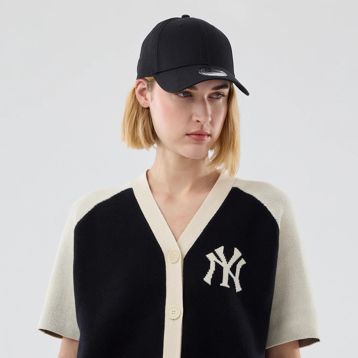 New Era New York Yankees Womens MLB Knit Stripe Black Short Sleeve Cardigan, on-model view showing the classic NY logo on the left chest, featuring black and cream knit fabric and a button-up front.