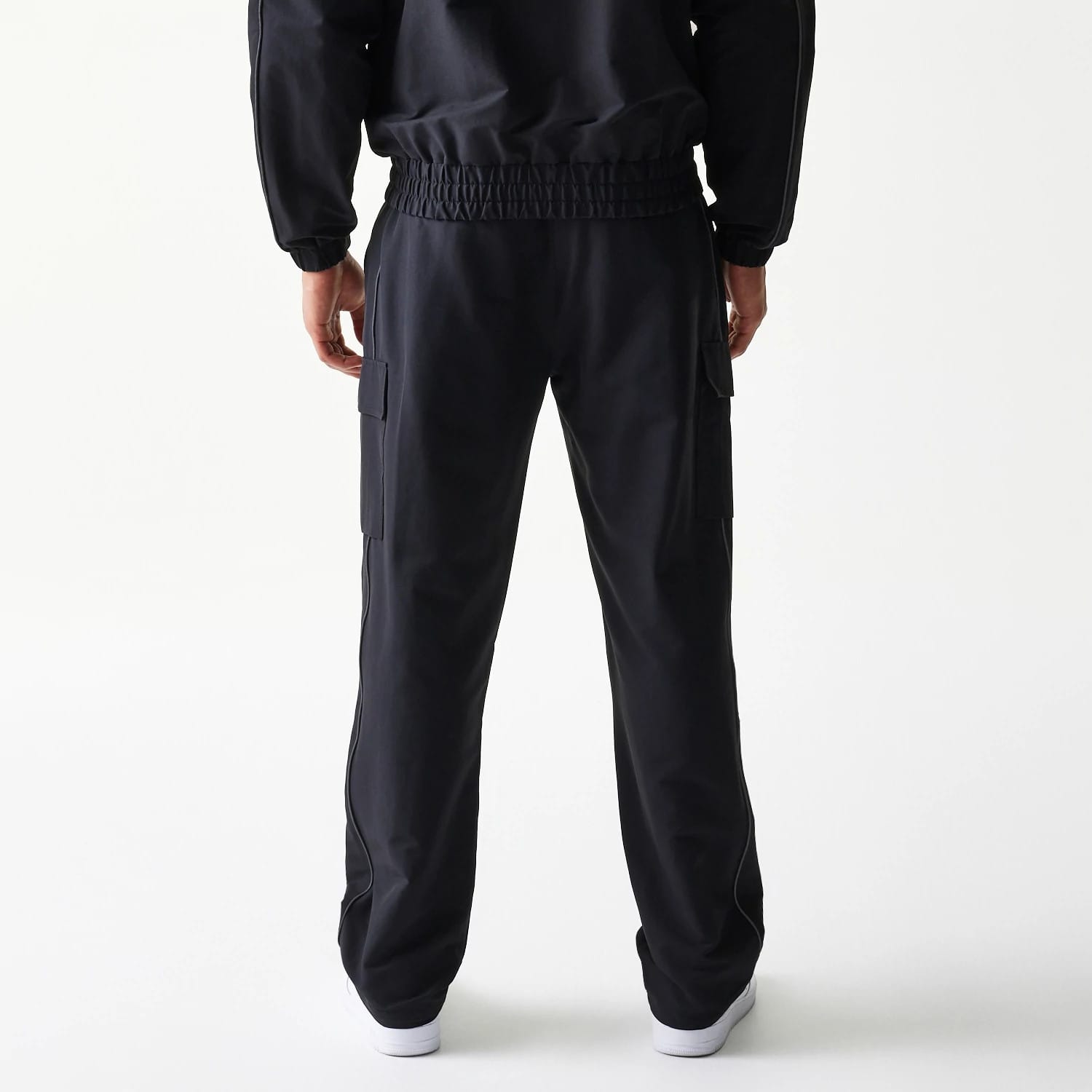 New Era New York Yankees MLB Utility Black Straight Leg Cargo Joggers, rear view on-model showing black elasticated waistband, cargo pockets on the sides, and a relaxed straight-leg fit, styled with a matching black jacket.