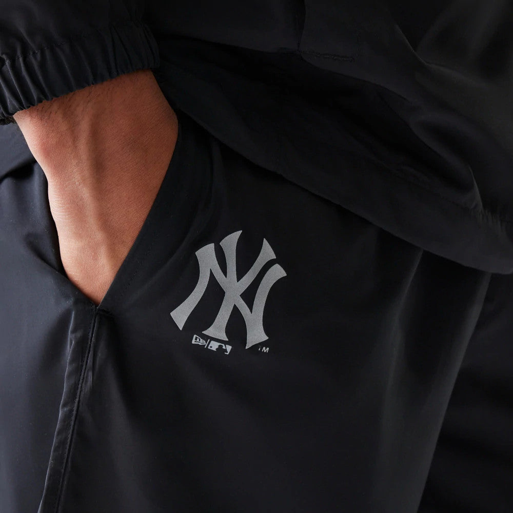 The model is wearing this MLB Reflective Logo New York Yankees Track Pants in black. 3