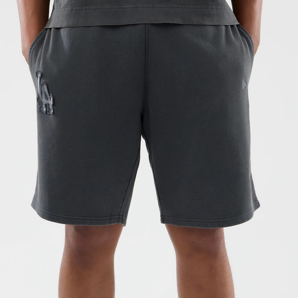 New Era LA Dodgers MLB Washed Dark Grey Shorts, back view showing the dark grey fabric with a raised LA Dodgers logo on the left leg, an embroidered New Era logo on the right leg, and side pockets.