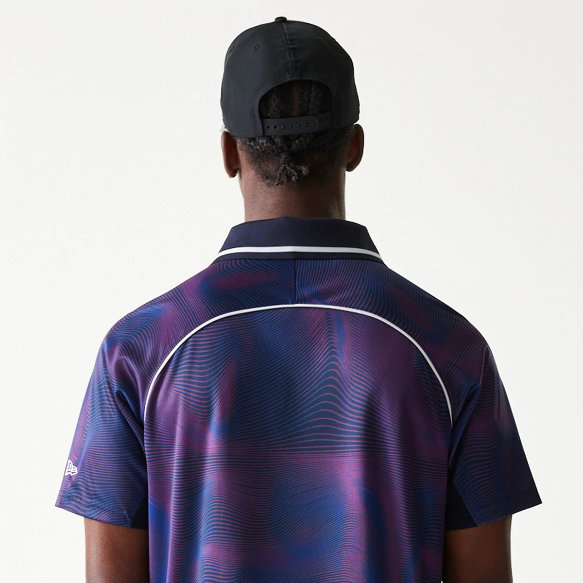 New Era Red Bull Racing All Over Print Dark Blue Football T-Shirt, back view on-model displaying an abstract wave pattern in shades of purple on dark blue, with white piping details along the shoulders and an embroidered New Era logo on the sleeve.