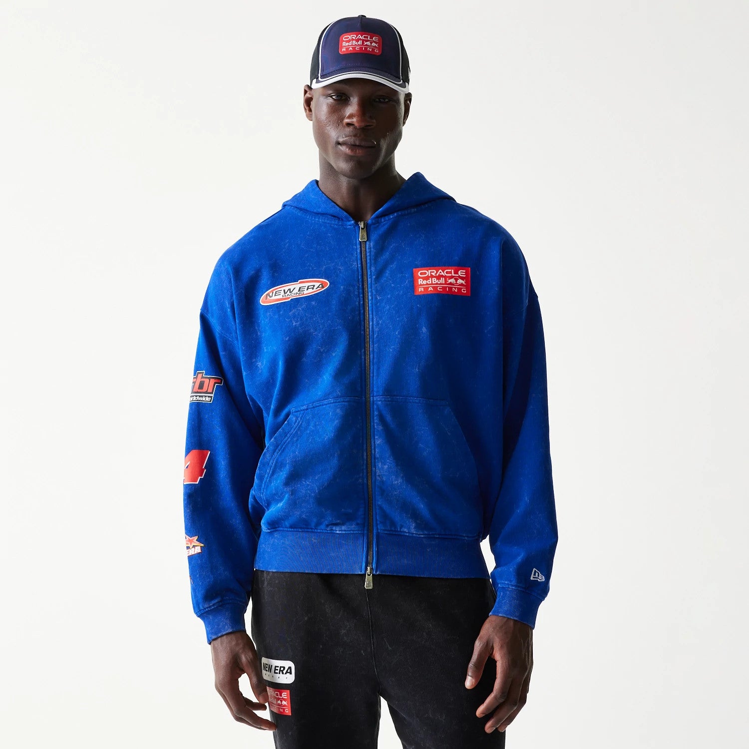 The model is wearing this Red Bull Racing Graphic Dropped Shoulder Full Zip Hoodie in blue. 1