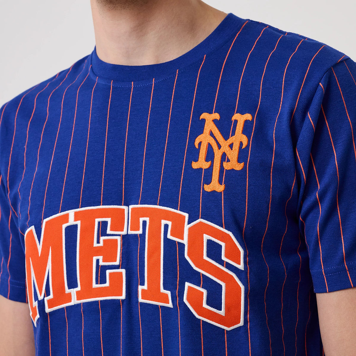 New Era New York Mets MLB Pinstripe Blue T-Shirt, front view showing blue fabric with orange pinstripes, the embroidered Mets logo on the left chest, and orange and white Mets lettering across the front.