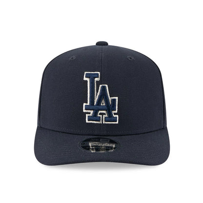 LA Dodgers MLB Navy New Era 9SEVENTY Stretch Snap Adjustable Cap, front view showing white outlined navy LA logo in raised embroidery on the structured crown, with a 9SEVENTY size sticker on the curved visor.