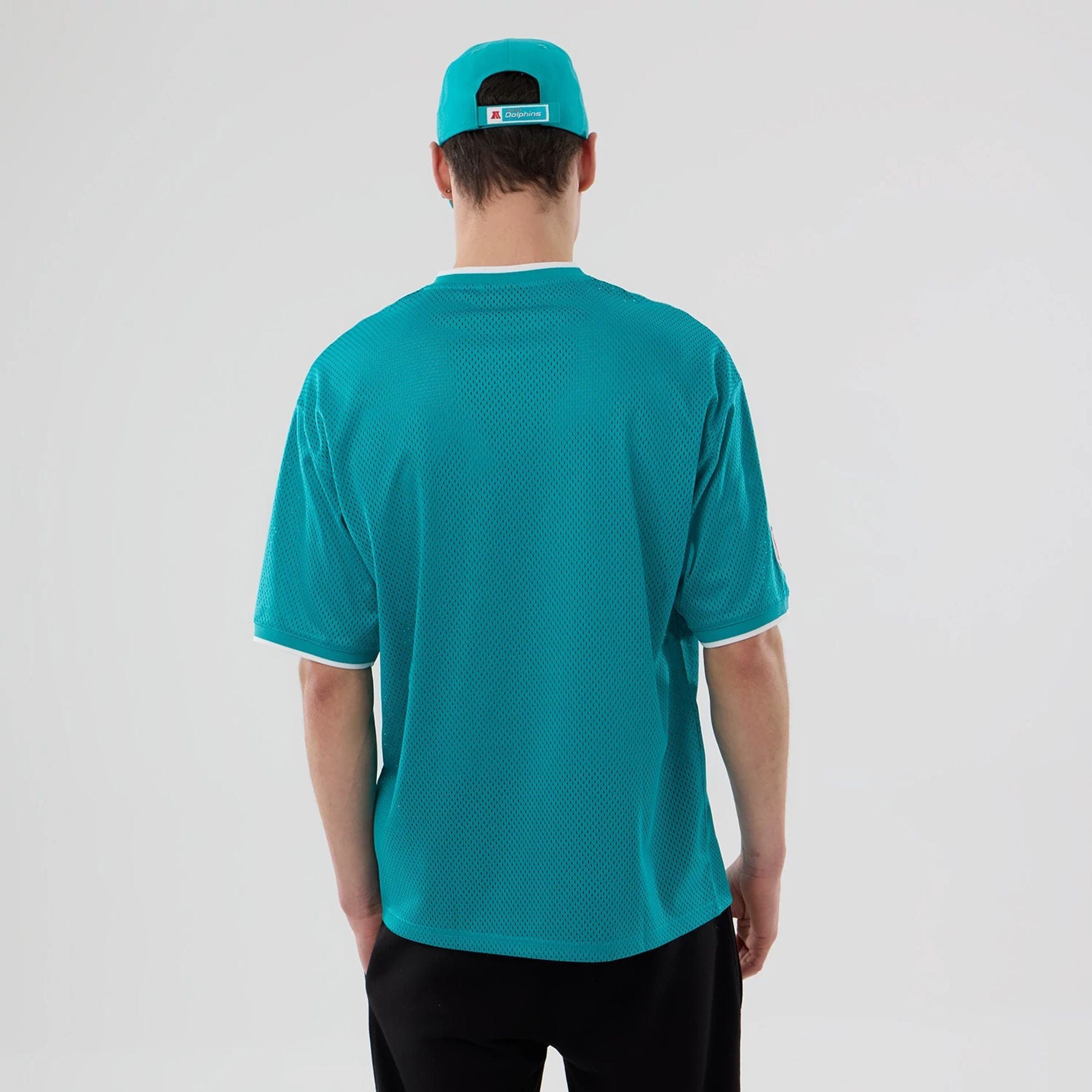 The model is wearing this NFL Mesh Miami Dolphins Oversized T-Shirt in turquoise. 2