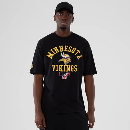 The Male model is wearing Minnesota Vikings NFL International Series Games 2025 Black Oversized T-Shirt  1