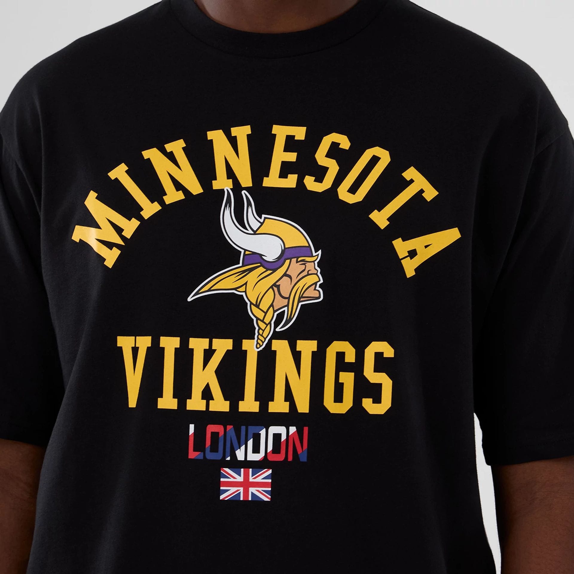 The Male model is wearing Minnesota Vikings NFL International Series Games 2025 Black Oversized T-Shirt 3