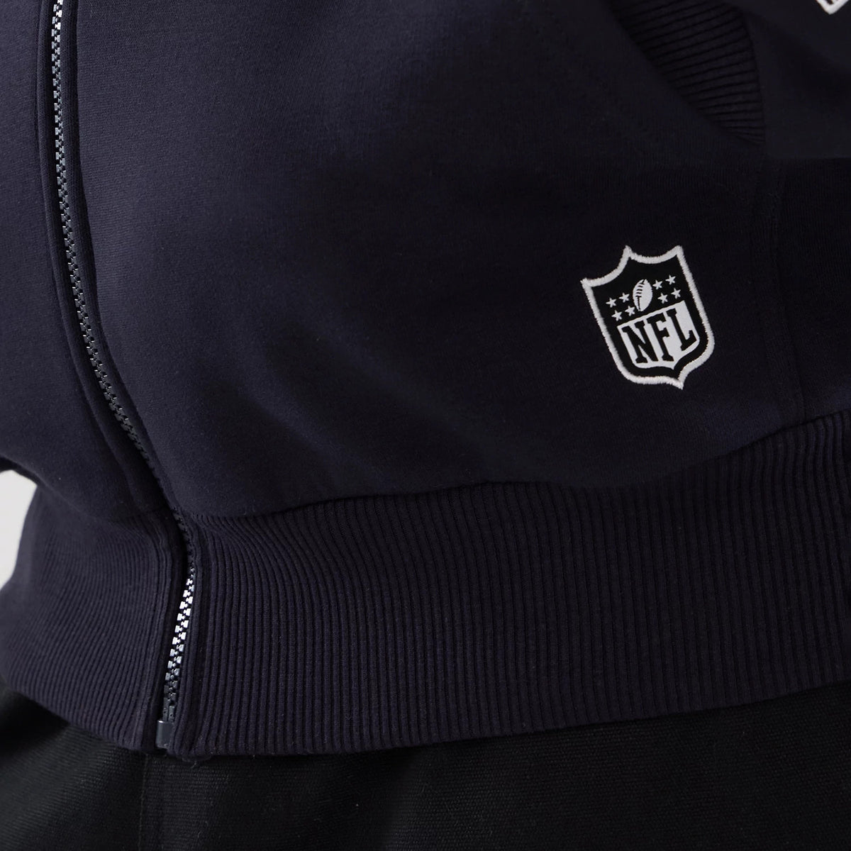 New Era LA Rams NFL International Series Games 2025 Navy Premium Pullover Hoodie, side view displaying a ribbed navy hem and a raised white NFL logo near the side seam, with a detailed zipper edge on the close-up fabric.