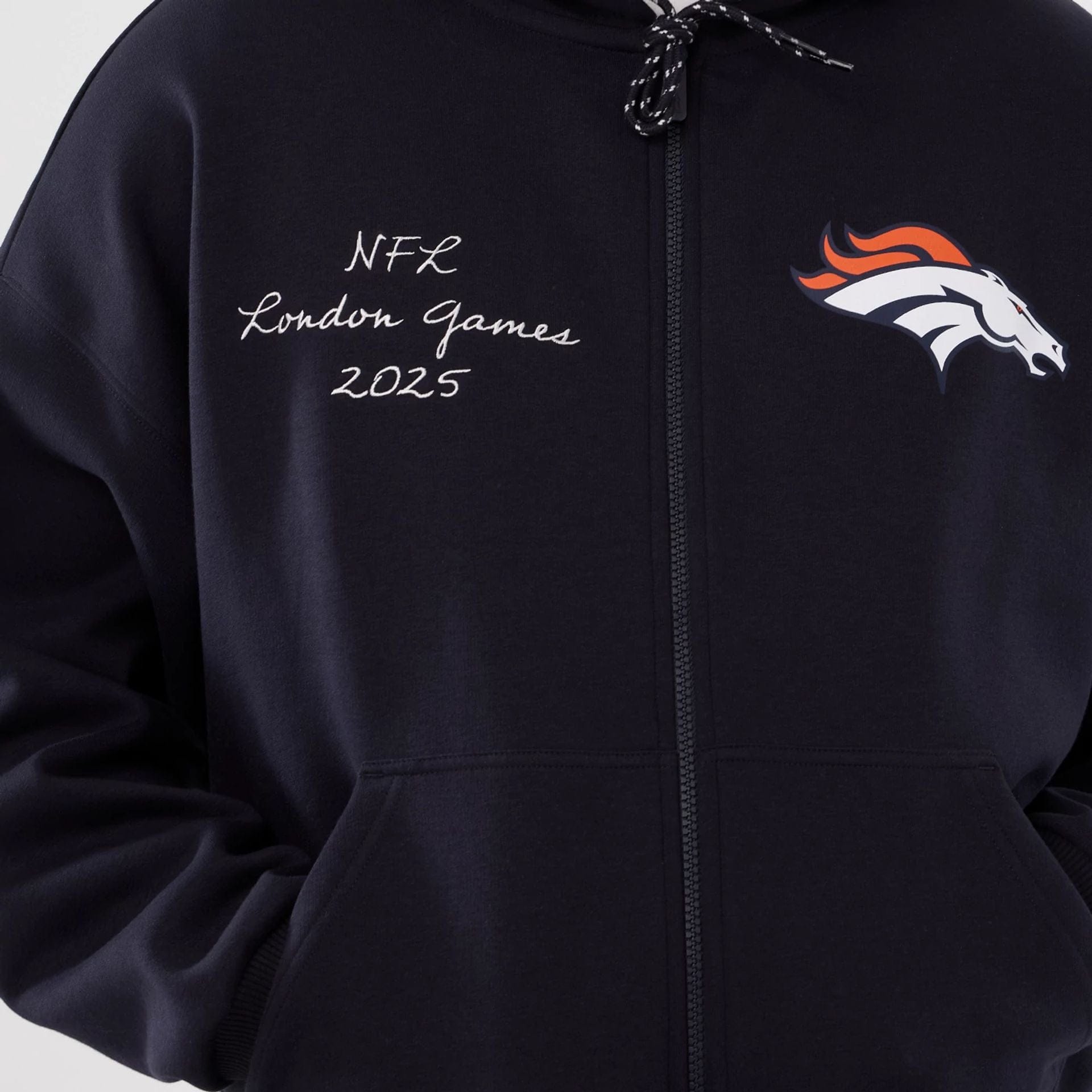 The Male model is wearing Denver Broncos NFL International Series Games 2025 Navy Premium Pullover Hoodie  3