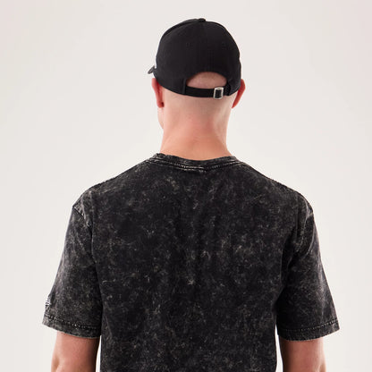 New Era Rick And Morty Science Black T-Shirt, back view on a model with a dark cap, shows a mottled black and grey pattern across the fabric, short sleeves, and an embroidered New Era logo on the left sleeve.
