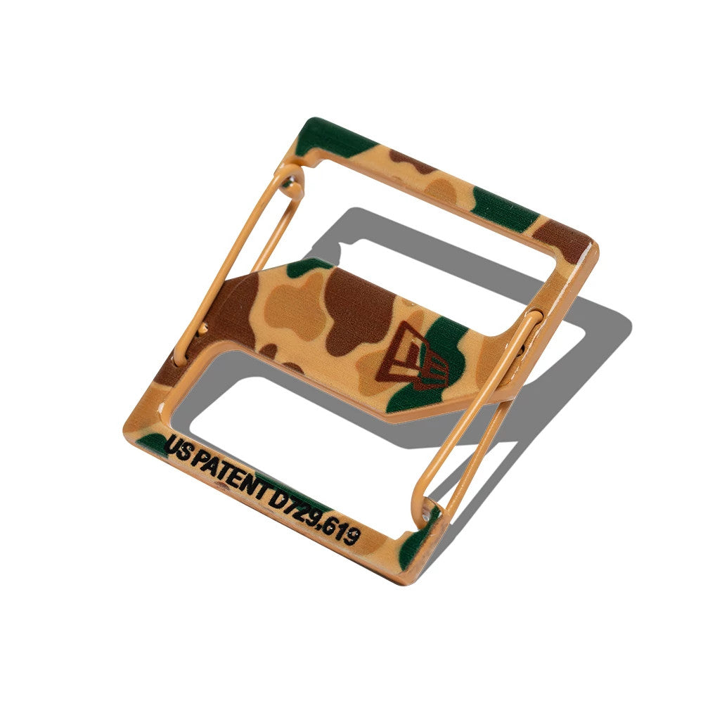 New Era Duck Camo Cap Clip, angled view showing a camouflage pattern with shades of brown and green, featuring the New Era flag logo in the centre and the text US PATENT D729.619 displayed at the bottom edge.