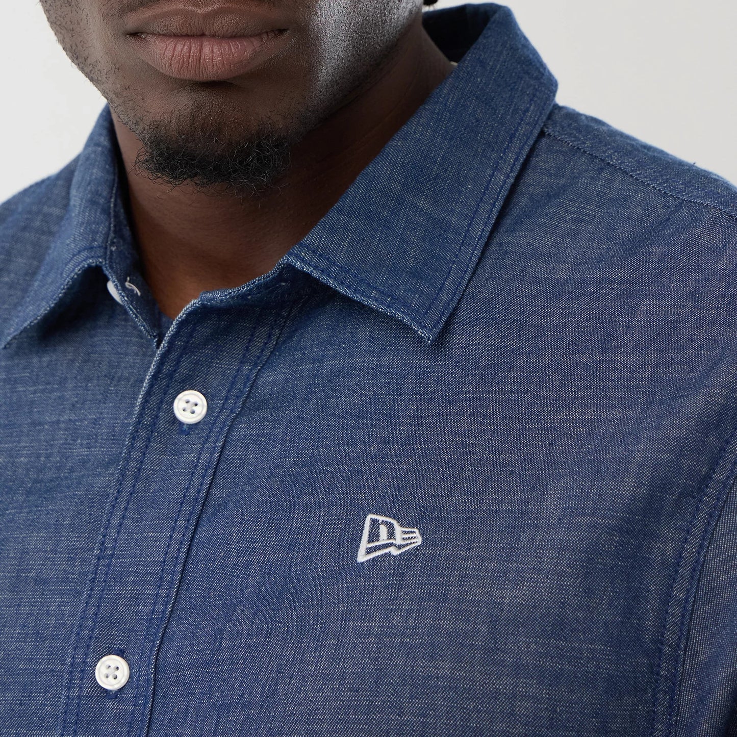 The model is wearing this New Era Denim Short Sleeve Shirt in blue. 4