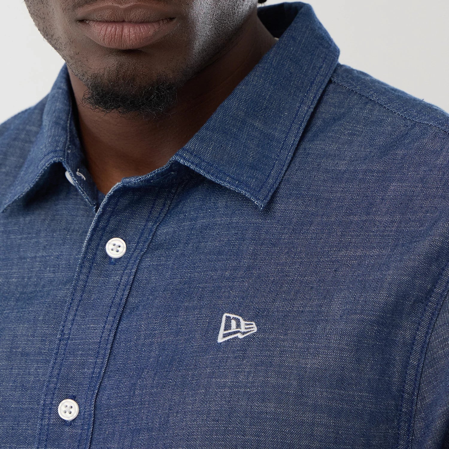 The model is wearing this New Era Denim Short Sleeve Shirt in blue. 4