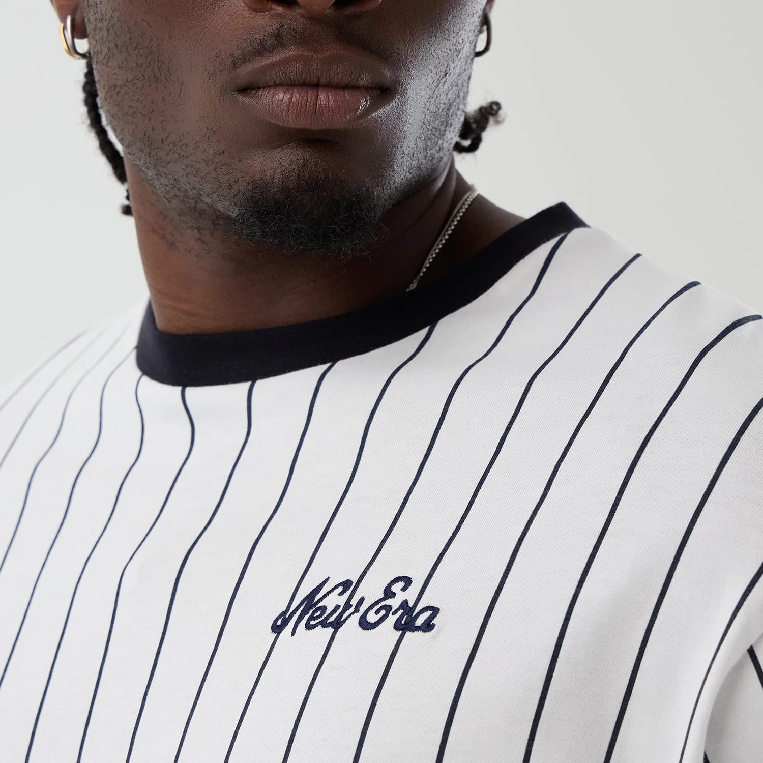 The model is wearing this New Era Pinstripe Oversized T-Shirt in Open White. 3