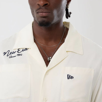 The model is wearing this New Era Graphic Revere Short Sleeve Shirt in open white. 5