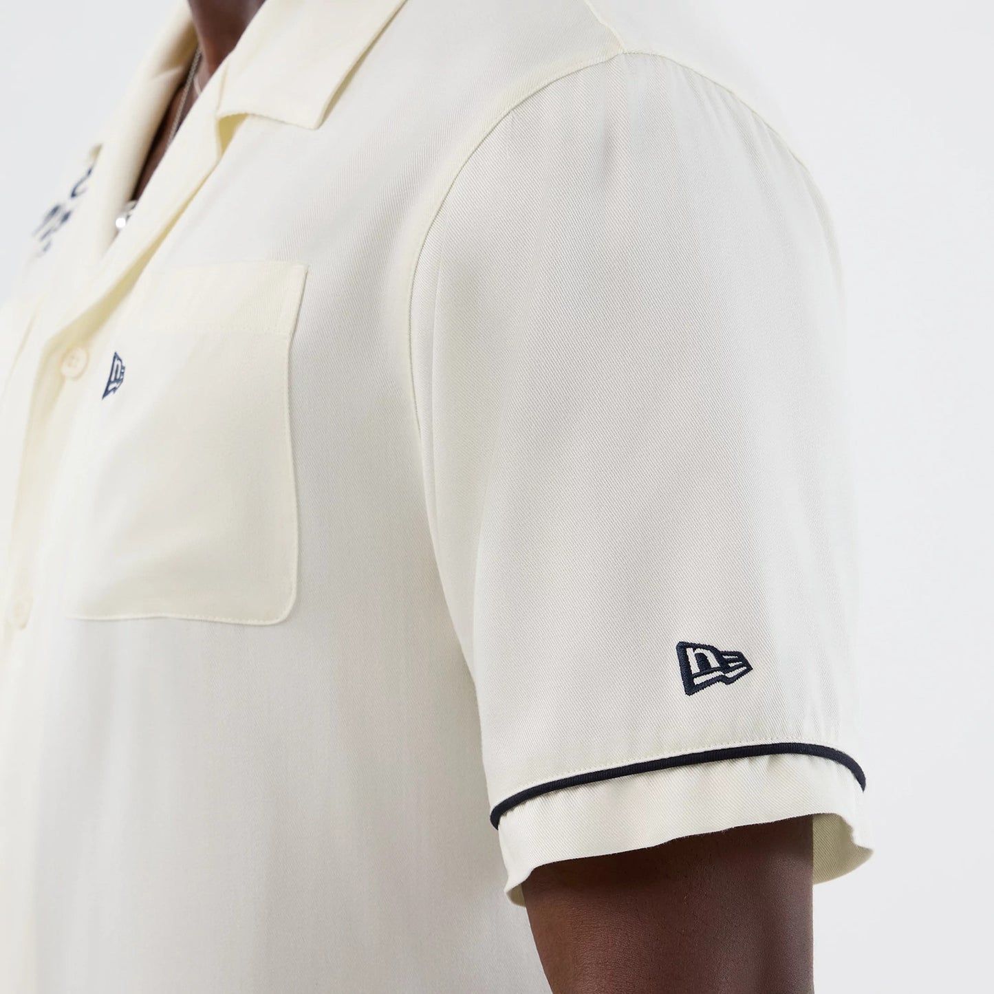 The model is wearing this New Era Graphic Revere Short Sleeve Shirt in open white. 6