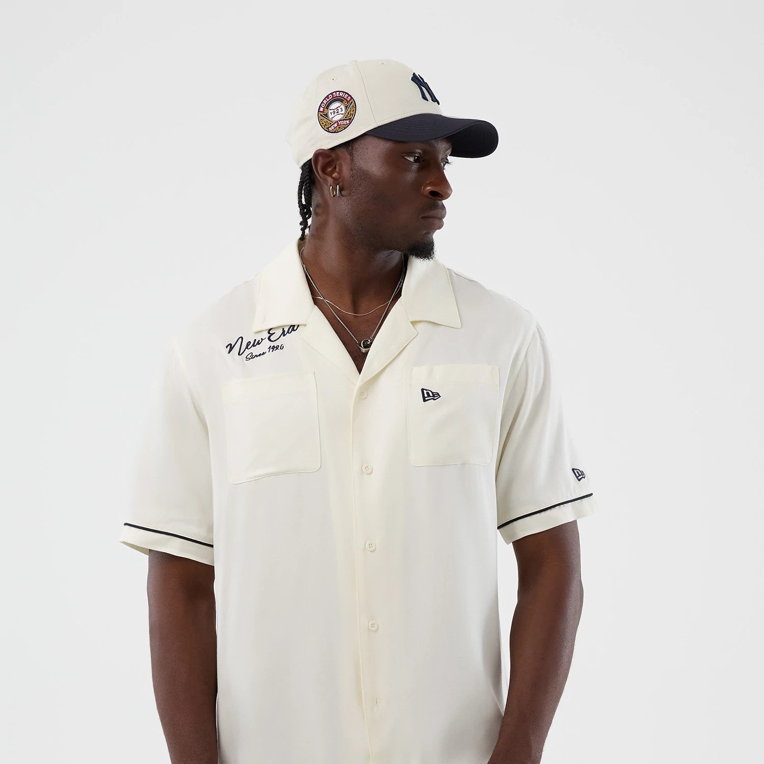 The model is wearing this New Era Graphic Revere Short Sleeve Shirt in open white. 7