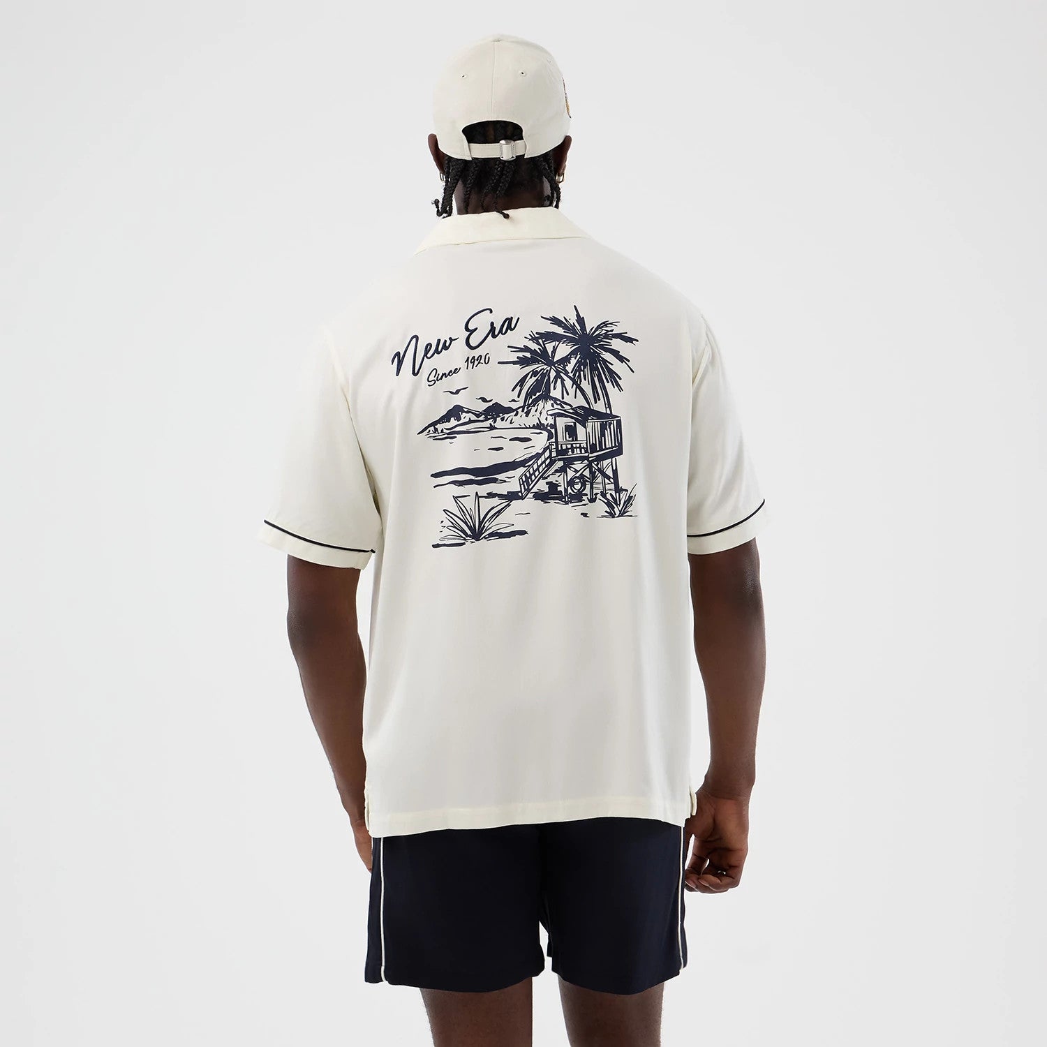 The model is wearing this New Era Graphic Revere Short Sleeve Shirt in open white. 2