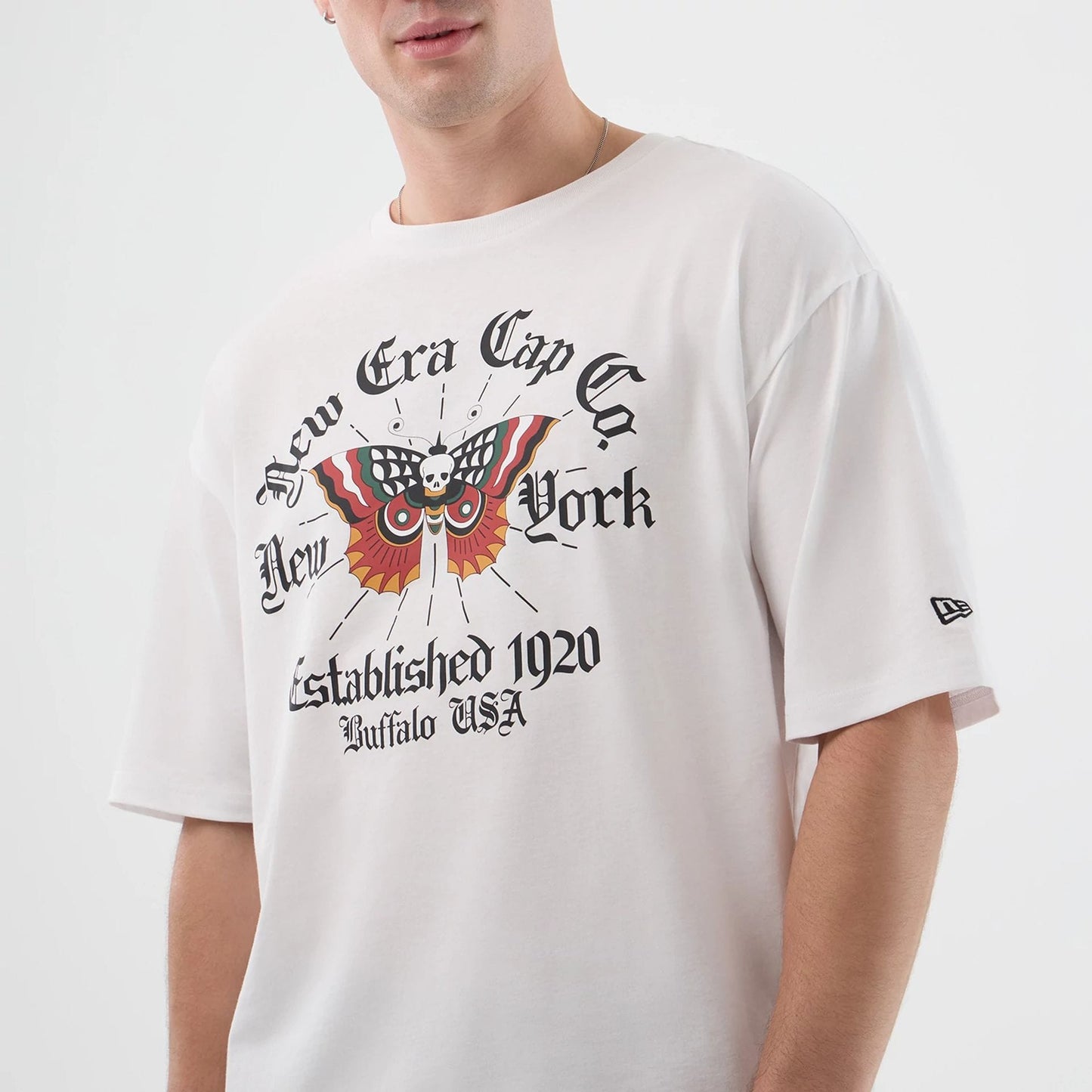 The model is wearing this New Era Death Moth Graphic Oversized T-Shirt in white. 6