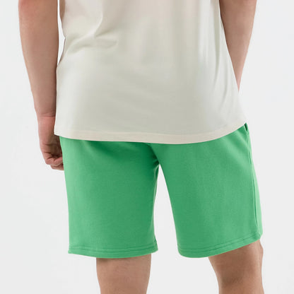 New Era LA Dodgers MLB League Essential Open Green Shorts, back view on a model paired with a cream top, showcasing the green colour and knee-length cut, with a simple design free from logos or graphics.