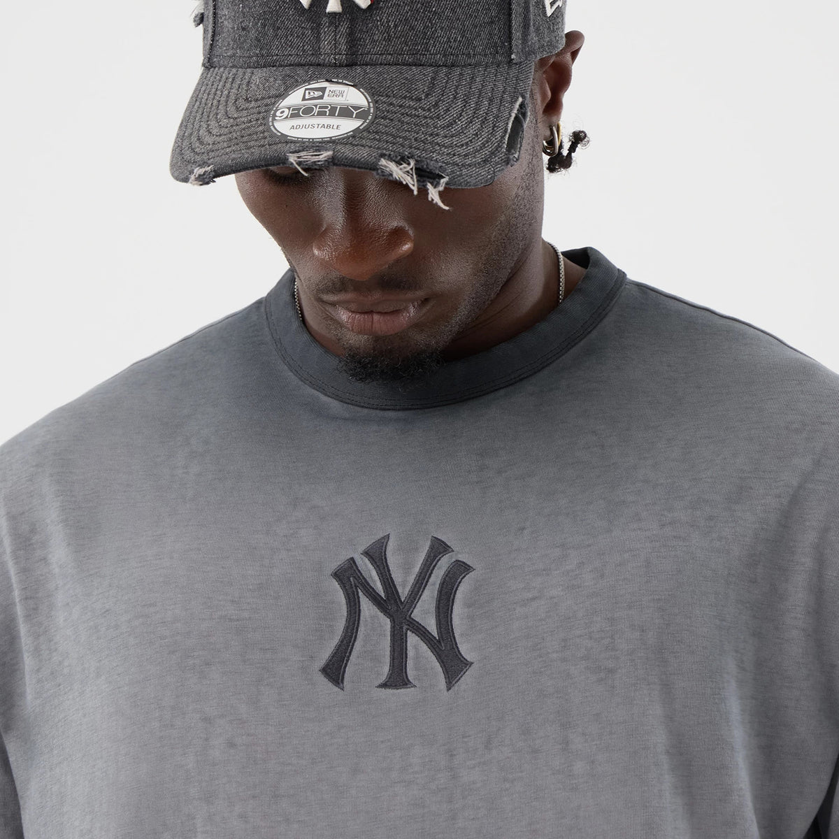 New Era New York Yankees MLB Washed Logo Black T-Shirt, front view on-model showing the black embroidered New York Yankees logo centred on the chest, styled with a distressed New York Yankees cap featuring a silver sticker on the visor.