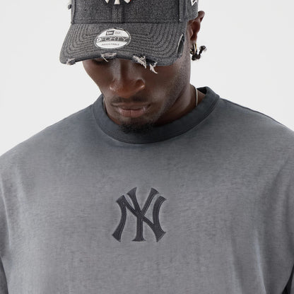 New Era New York Yankees MLB Washed Logo Black T-Shirt, front view on-model showing the black embroidered New York Yankees logo centred on the chest, styled with a distressed New York Yankees cap featuring a silver sticker on the visor.