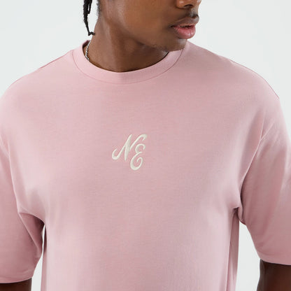 New Era Floral Graphic Pastel Pink Oversized T-Shirt, front view showing a embroidered NE logo in white on the upper chest, the relaxed fit with short sleeves and a pastel pink theme worn by a model from the shoulders up.