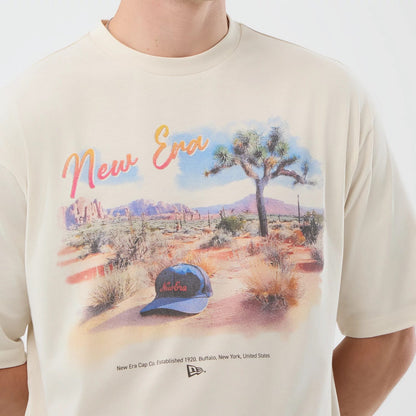 The model is wearing this New Era Dessert Graphic Oversized T-Shirt in light beige. 5