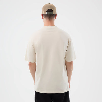 The model is wearing this New Era Dessert Graphic Oversized T-Shirt in light beige. 2