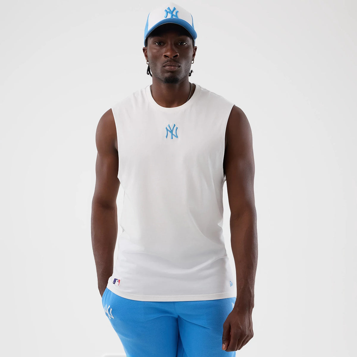 New Era New York Yankees MLB League Essential White Vest, front view on a model paired with a matching cap, featuring a light blue embroidered NY logo on the chest and a small MLB Batterman patch near the waist.