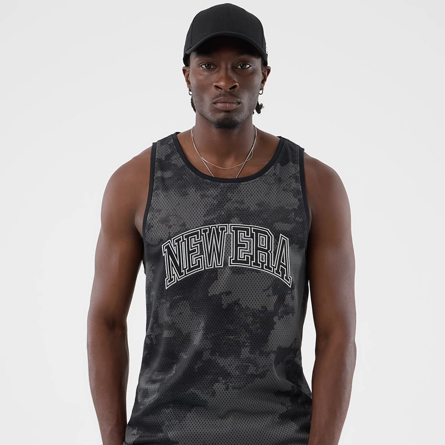 The model is wearing this New Era All Over Print Mesh Tank Top in black camo. 3