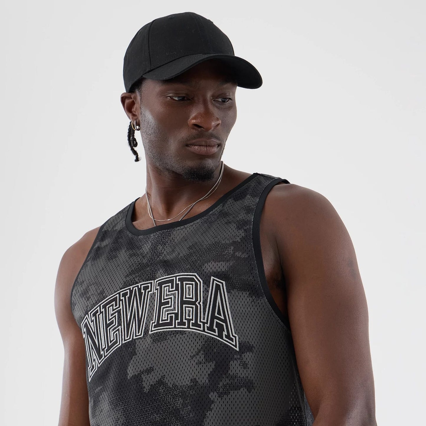 The model is wearing this New Era All Over Print Mesh Tank Top in black camo. 4