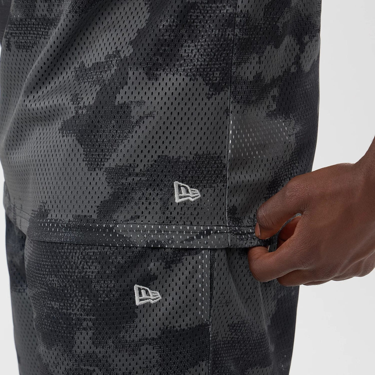 The model is wearing this New Era All Over Print Mesh Tank Top in black camo. 5