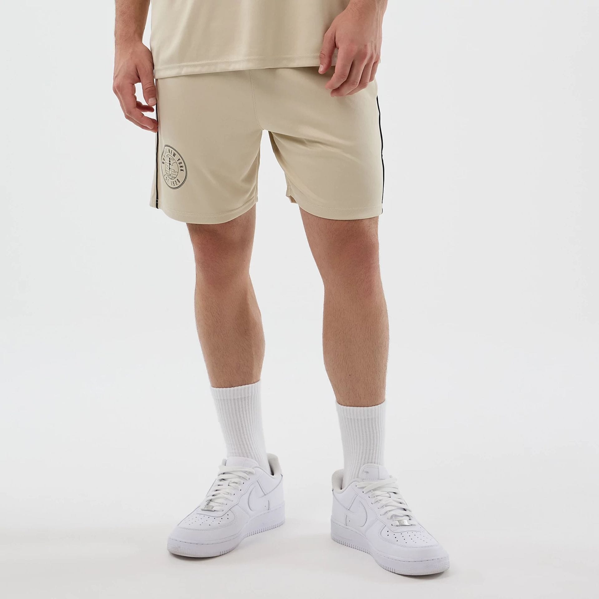 The model is wearing these New Era Football Shorts in light beige. 1