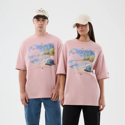 The model is wearing this New Era Beach Graphic Oversized T-Shirt in pastel pink. 1