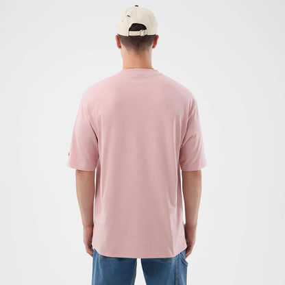 The model is wearing this New Era Beach Graphic Oversized T-Shirt in pastel pink. 2